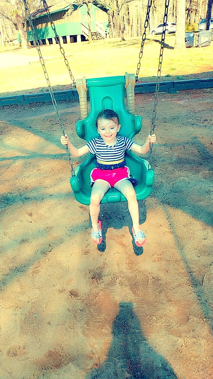 Erica is registered to the contest to win money with this photo: baby_toddler_clothing, balance, child, city, electric_blue, fun, grass, happy, joy, leisure, outdoor_play_equipment, people_in_nature, person, play, playground, recreation, rope, shorts, smile, swing