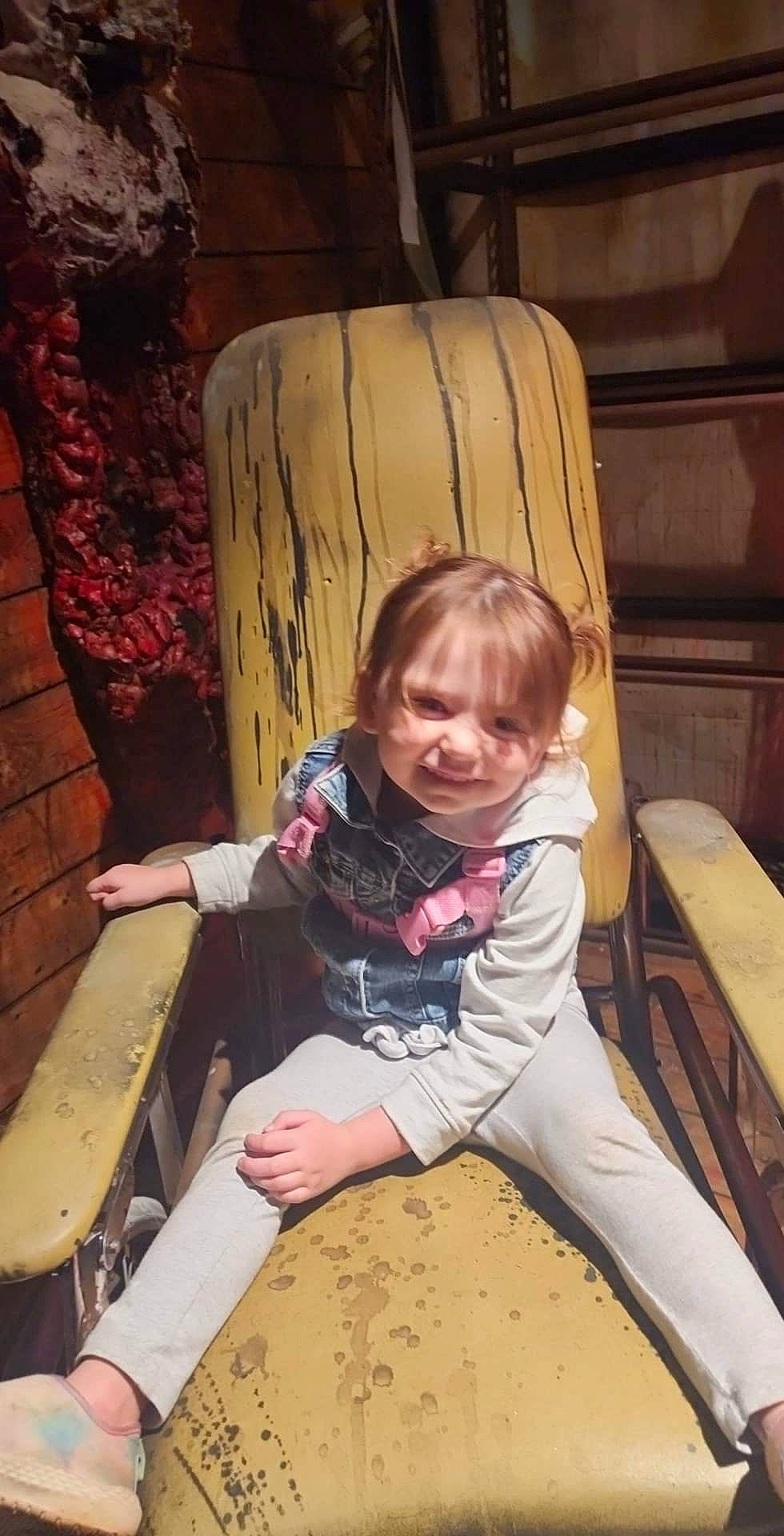Erica is registered to the contest to win money with this photo: bench, chair, child, comfort, flooring, fun, hardwood, human_leg, leisure, person, play, recreation, room, sitting, smile, sunglasses, thigh, toddler, tree, vacation