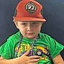 Joseph joined the competition — help win amazing prizes! child, boy, cap, hat, green_shirt, necklace, beads, couch, seated, casual_clothing, indoor, portrait, young, face, expression, hand, furniture, comfortable, relaxed, colorful