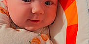 Nora is registered to the contest to win money with this photo: baby, infant, face, blanket, pattern, pumpkin, play_mat, stars, circle, smile, closeup, child, cute, soft_lighting, indoors, wrapped, comfort, young, person, portrait