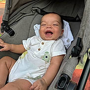 Thiago participe au concours pour gagner de l'argent avec cette photo : baby, child, stroller, smiling, laughing, onesie, white_clothing, infant, seat, fabric, cute, happy, outdoor, person, portrait, hand, leg, head, baby_clothes, comfort
