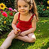 Natalie is registered to the contest to win money with this photo: child, girl, smiling, red_dress, grass, flowers, garden, sunlight, outdoor, nature, greenery, happy, playing, summer, portrait, sitting, cute, young, person, daylight