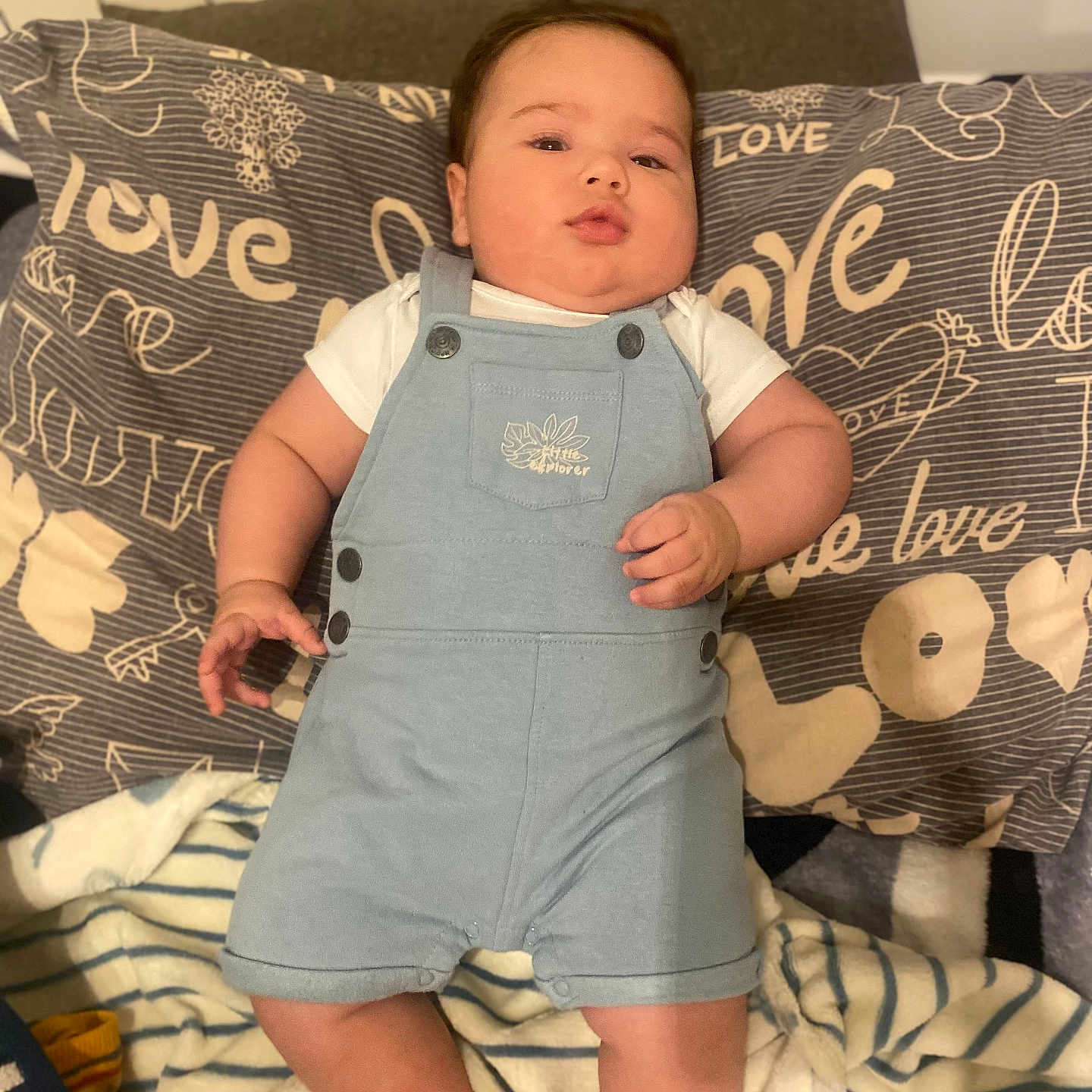 Dominic Alexandru a rejoint le concours — aidez-le/la à gagner de superbes lots ! arm, baby, bed, blanket, child, clothing, cute, head, indoors, infant, leg, love_text, person, pillow, relaxed, resting, romper, skin, soft_texture, striped_blanket