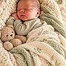 newborn, baby, sleeping, infant, portrait, cozy, blanket, swaddle, teddy_bear, stuffed_animal, bed, indoors, soft_lighting, warm_tones, knitwear, peaceful, nursery, closeup, resting, adorable