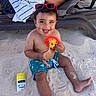 barefoot, beach, child, curly_hair, happy, outdoor, playful, relaxation, sand, sand_on_skin, smiling, summer, sun_protection, sunglasses, sunny_day, sunscreen, swim_shorts, toddler, toy, vacation