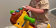 Bentley joined the competition — help win amazing prizes! baby, child, toy, horse, indoor, carpet, smiling, happy, toddler, play, colorful, plastic, wheels, clothing, shorts, shirt, hand, foot, person, window