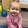 Paige joined the competition — help win amazing prizes! toddler, child, smiling, pink_clothing, toy, playroom, blue_ball, wooden_bed, flooring, hair_tied, happy, indoor, person, candid, cute, young_child, baby, floor_mat, playful, portrait
