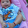 Briella is registered to the contest to win money with this photo: baby, child, smiling, headband, tshirt, cartoon, pink_cushion, outdoor, grass, happy, infant, blue_shorts, foot, hand, relaxing, portrait, cute, playful, sunlight, comfortable
