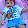baby, smiling, headband, red, blue_shorts, tshirt, cartoon, pink_cushion, seat, outdoor, grass, happy, child, infant, person, cute, leisure, playful, relaxing, wearing_clothes