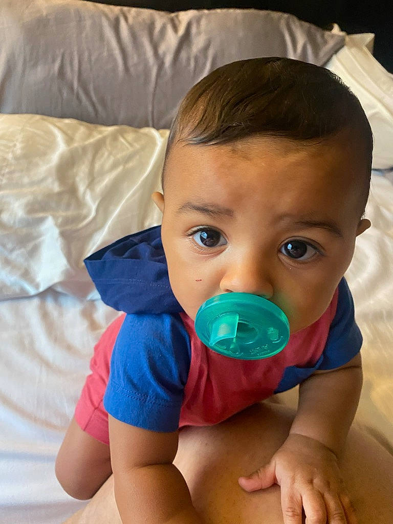 Maverick is registered to the contest to win money with this photo: baby, baby_toddler_clothing, cheek, child, comfort, drinkware, eye, face, fun, hair, happy, head, human_body, mouth, neck, person, plastic_bottle, t_shirt, textile, thumb