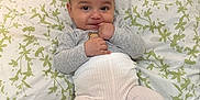 Erik is registered to the contest to win money with this photo: baby, infant, child, bed, pillow, blanket, clothing, socks, face, smile, cute, indoors, portrait, lying_down, cozy, home, soft, comfort, young, playful