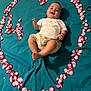 baby, infant, smile, rose_petals, heart_shape, blanket, teal, cute, happy, laying_down, clothing, hand, foot, portrait, indoors, flower_petals, love, baby_gesture, skin, head