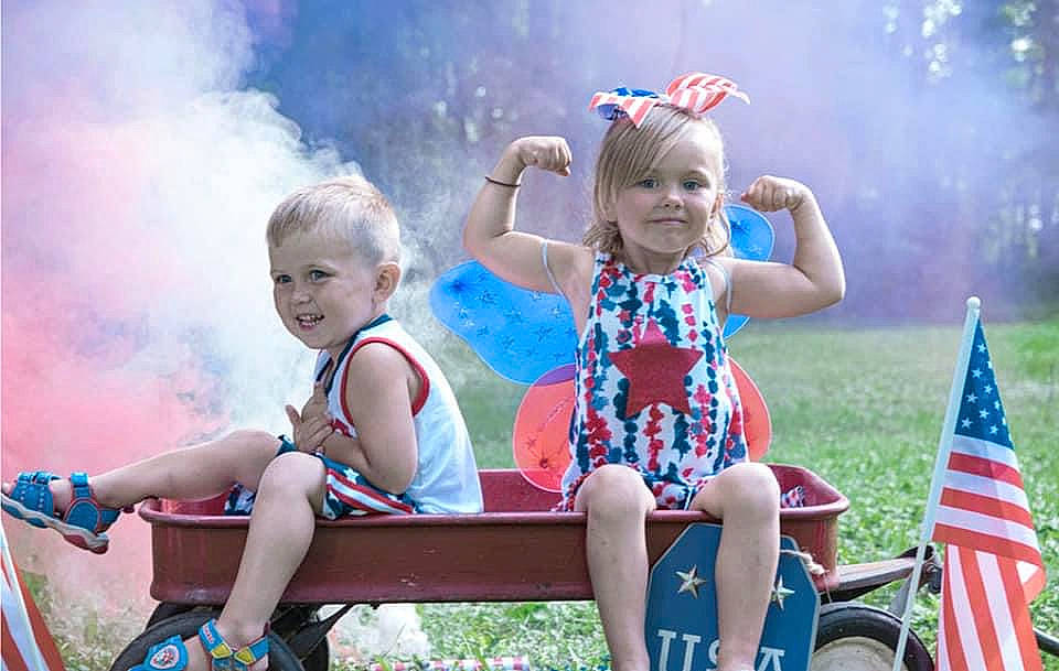 Mia is registered to the contest to win money with this photo: baby_toddler_clothing, blond, blue, event, flag, flag_of_the_united_states, flash_photography, fun, grass, happy, joy, leisure, people_in_nature, person, pink, recreation, shorts, sitting, smile, summer