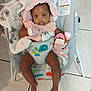 baby, infant, bouncer, blanket, pink_clothing, mittens, toy, floor_tiles, baby_seat, child, cute, indoor, toddler, colorful, animal_print, comfort, portrait, smiling, happy, seated