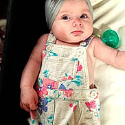 Willow joined the competition — help win amazing prizes! baby, child, headband, bow, floral, overalls, clothing, pacifier, infant, face, eyes, skin, arm, hand, lying_down, cute, expression, indoor, portrait, person