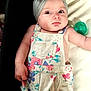 baby, child, headband, bow, floral, overalls, clothing, pacifier, infant, face, eyes, skin, arm, hand, lying_down, cute, expression, indoor, portrait, person