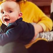 Gabriel a rejoint le concours — aidez-le/la à gagner de superbes lots ! baby, blurred_background, child, clothing, cozy, cute, expression, face, hands, happy, holding, indoor, infant, joyful, person, portrait, sitting, smiling, warm, yellow_sweater