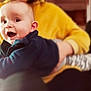 baby, blurred_background, child, clothing, cozy, cute, expression, face, hands, happy, holding, indoor, infant, joyful, person, portrait, sitting, smiling, warm, yellow_sweater