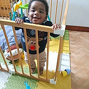 Uriel participe au concours pour gagner de l'argent avec cette photo : baby, child, clothing, colorful, floor, furniture, hand, happy, head, home, indoor, person, play_mat, reindeer, smiling, standing, sweater, toddler, toy, wooden_gate