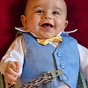 Alonzo joined the competition — help win amazing prizes! accessory, baby, blue_vest, child, closeup, clothing, cute, face, hand, happy, indoor, infant, lying_down, patterned_strap, person, portrait, red_background, smiling, white_shirt, yellow_bow_tie