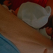 Mía participe au concours pour gagner de l'argent avec cette photo : baby, blanket, hat, person, arm, clothing, red_top, blue_blanket, beige_blanket, skin, hand, infant, newborn, warmth, snuggle, cozy, sleeping, resting, comfort, indoor