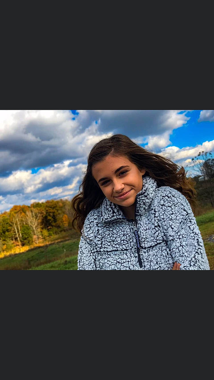 Lily is registered to the contest to win money with this photo: beauty, black_hair, brown_hair, cloud, eye, flash_photography, grass, happy, joy, long_hair, mountain, outerwear, person, photo_shoot, photograph, photography, portrait, portrait_photography, sitting, sky