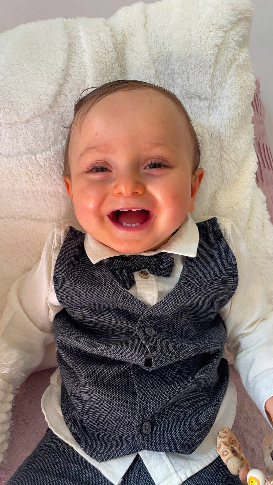Lissandro a rejoint le concours — aidez-le/la à gagner de superbes lots ! baby, blanket, bow_tie, cheerful, child, clothing, cute, face, happy, indoor, infant, person, portrait, sitting, smiling, soft_texture, toy, vest, white_shirt, young_child