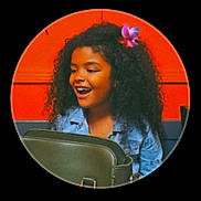 Sofia a rejoint le concours — aidez-le/la à gagner de superbes lots ! child, girl, curly_hair, flower, denim_jacket, bag, orange_background, happy, smiling, portrait, indoor, black_hair, casual_clothing, young, fashion, accessory, candid, expression, colorful, fun