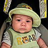 baby, infant, child, portrait, car_seat, sun_hat, green_clothing, tiger, roar, serious_expression, face, eyes, indoor, close_up, seated, blanket, automobile, safety_warning, textile, photography