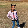 child, girl, smiling, outdoor, grass, sunlight, posing, hair_buns, braids, beads, cardigan, jeans, boots, pink, blue, black, casual_clothing, happy, portrait, nature