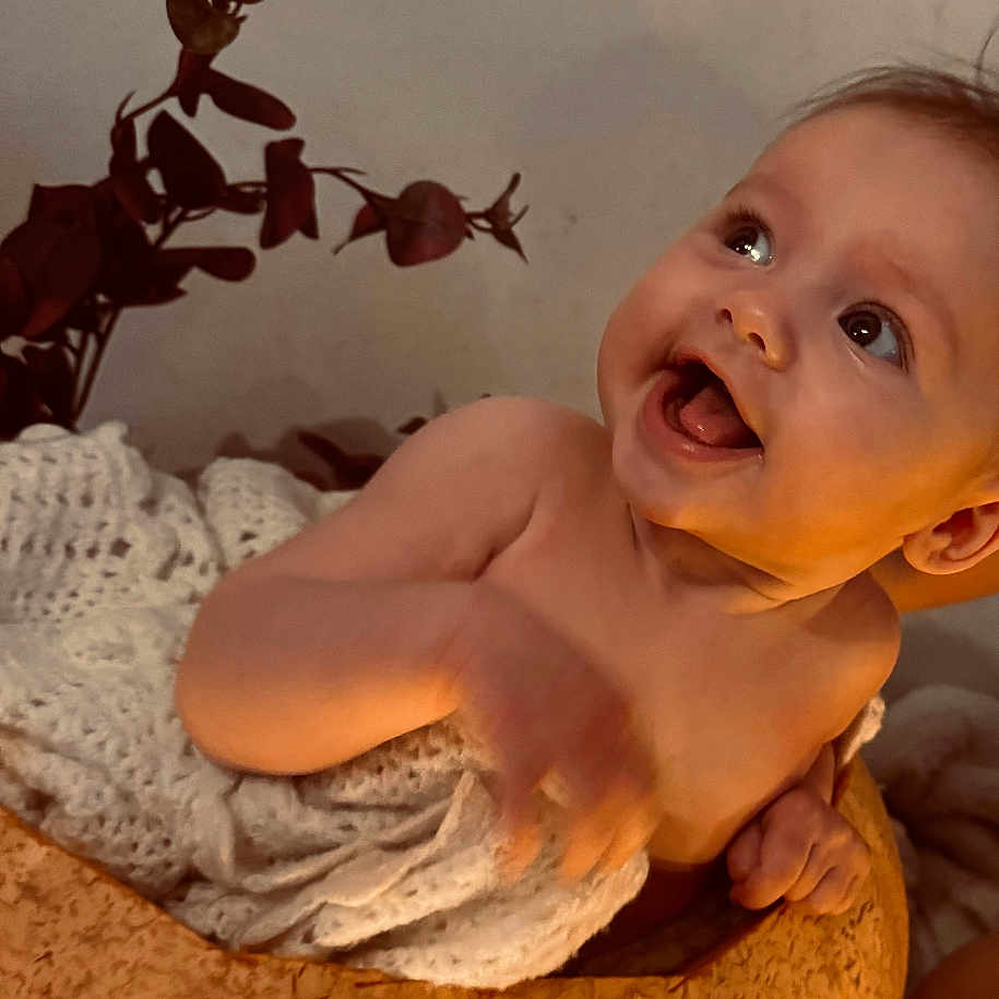 Muriel joined the competition — help win amazing prizes! ankle, baby, babylaughing, bodypart, clothing, dress, face, finger, hand, happy, head, laughing, mouth, newborn, person, photography, portrait, sitting, smile, towel