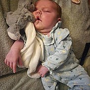 Lottie is registered to the contest to win money with this photo: baby, sleeping, stuffed_toy, bunny, blanket, pacifier, blue_onesie, soft_toy, infant, child, cozy, cute, comfort, resting, peaceful, furniture, indoors, portrait, hand, footwear