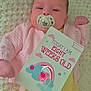Lottie is registered to the contest to win money with this photo: baby, infant, pacifier, milestone_card, blanket, knitted, pink_clothing, yellow_shirt, striped_pants, face, person, cute, newborn, lying_down, indoor, soft_lighting, portrait, child, smiling, hand
