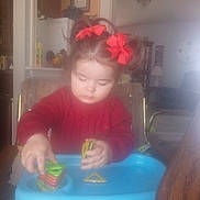 Emmy Ray joined the competition — help win amazing prizes! toddler, child, red_bows, magnetic_shapes, blue_tray, cocomelon, indoor, home, high_chair, playing, toy, concentration, furniture, clock, chair, table, living_room, sweater, hair, person