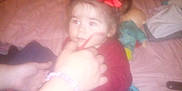Emmy Ray is registered to the contest to win money with this photo: toddler, child, red_bow, red_shirt, jeans, bed, hand, doll, toy, indoor, person, face, candid, soft_focus, blur, casual, family, home, sitting, cozy