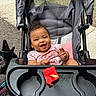 baby, stroller, watermelon, smiling, child, outdoor, dog, pink_clothing, seat, tray, happy, person, food, animal, leash, pavement, grass, hand, face, cute