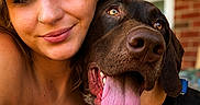 Penelope joined the competition — help win amazing prizes! woman, dog, portrait, smiling, close_up, tattoo, nose_ring, tongue_out, pet, leash, outdoor, brick_wall, porch, happy, friendship, face, skin, hair, collar, warm_light