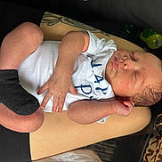 Kyaire is registered to the contest to win money with this photo: newborn, baby, sleeping, arm, tattoo, onesie, black_socks, person, hand, skin, purse, fabric, closeup, infant, resting, cute, peaceful, human, casual, indoor