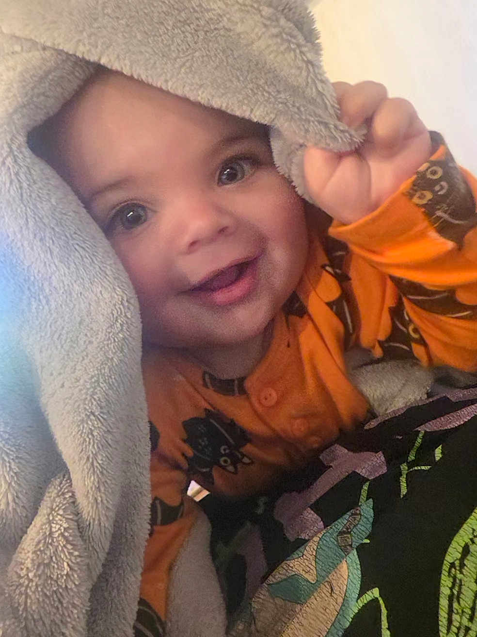 Malakai is registered to the contest to win money with this photo: toddler, child, smiling, blanket, orange_clothing, face, happy, baby, cute, indoor, hand, eyes, portrait, cozy, fabric, comfort, playful, closeup, expression, young