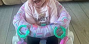 Paisley joined the competition — help win amazing prizes! baby, baby_seat, child, clothing, couch, cute, face, floor, footwear, gold_shoes, happy, headband, indoors, infant, joyful, pink_shirt, sitting, smiling, toy_rings, young_child