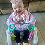 baby, smiling, infant, child, headband, gold_shoes, pink_shirt, baby_seat, toy_rings, floor, couch, happy, indoors, cute, sitting, clothing, footwear, face, young_child, joyful