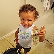 Ashton joined the competition — help win amazing prizes! child, toddler, curly_hair, smiling, money, dollar_bill, white_shirt, graphic_tshirt, socks, tile_floor, bathroom, rug, door, towel, indoor, person, standing, cute, playful, expression