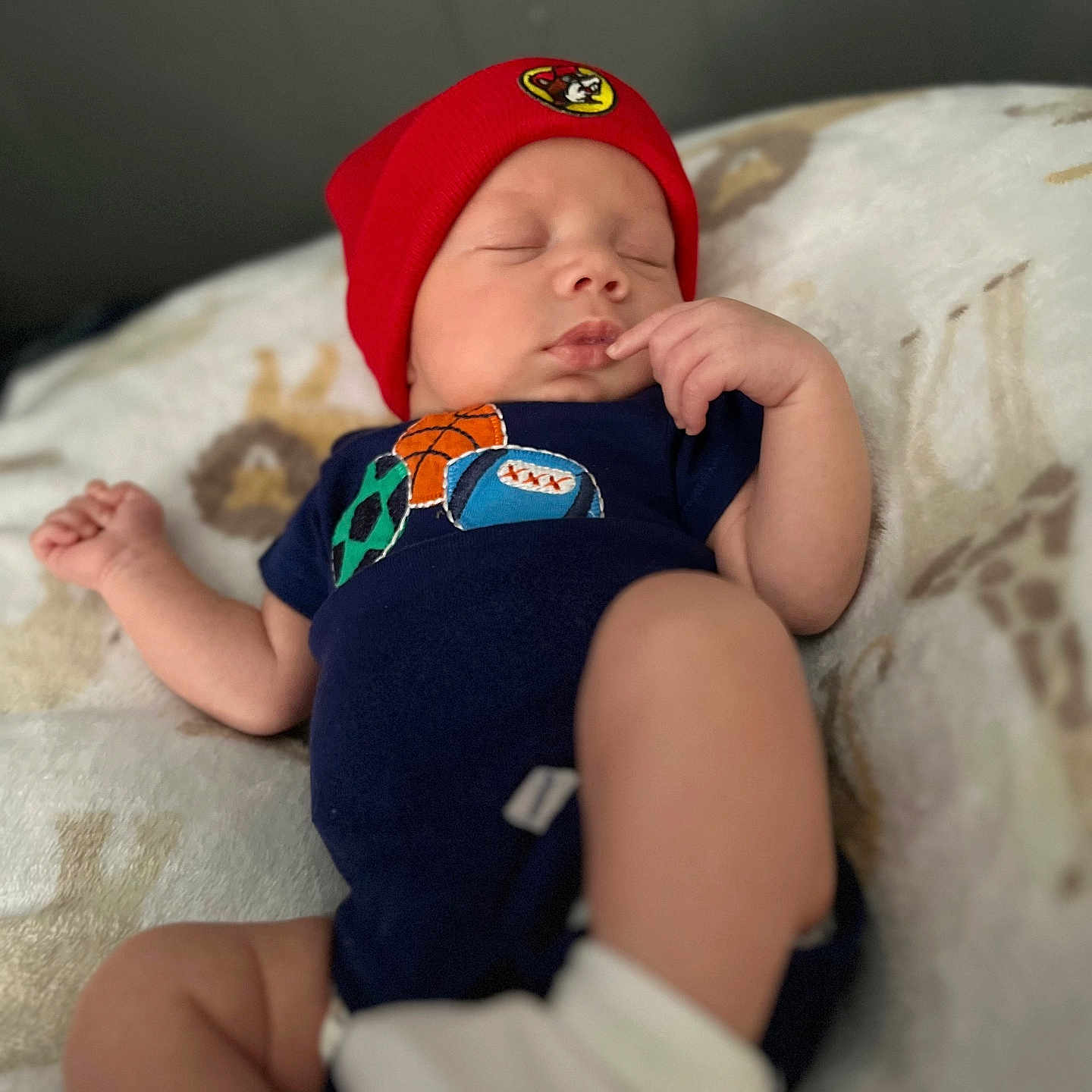 Kessiah is registered to the contest to win money with this photo: baby, babywear, blanket, child, clothing, cute, headwear, indoor, infant, newborn, onesie, peaceful, person, portrait, red_hat, resting, sleeping, sock, soft_focus, sports_balls