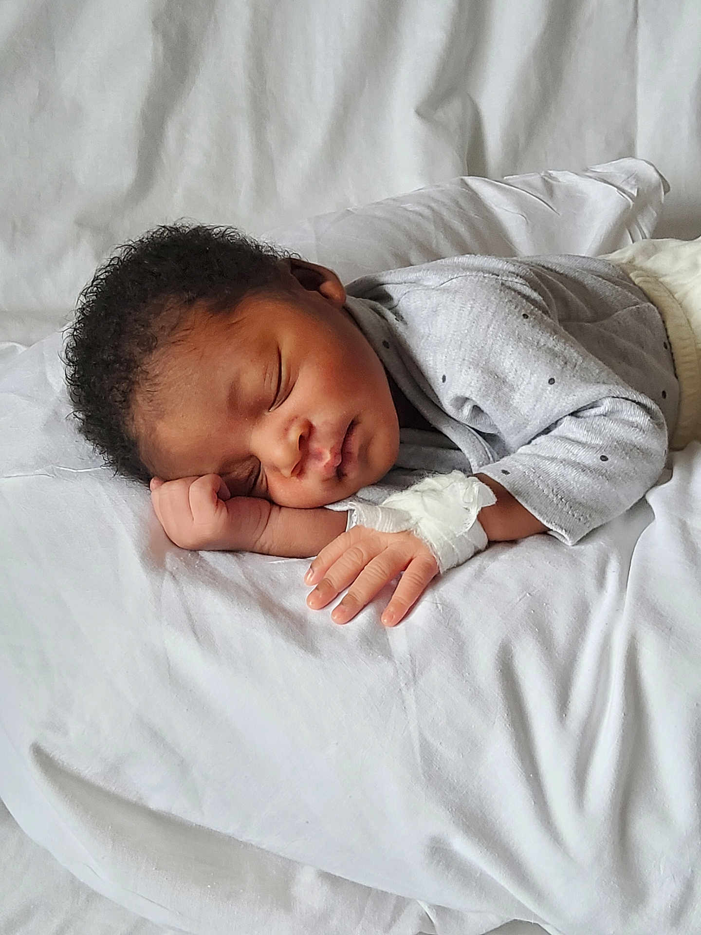 Andy Thomas a rejoint le concours — aidez-le/la à gagner de superbes lots ! baby, sleeping, infant, curly_hair, hospital_bandage, grey_clothing, white_bed, peaceful, resting, child, portrait, soft_light, indoors, closeup, newborn, hand, face, cute, cozy, blanket