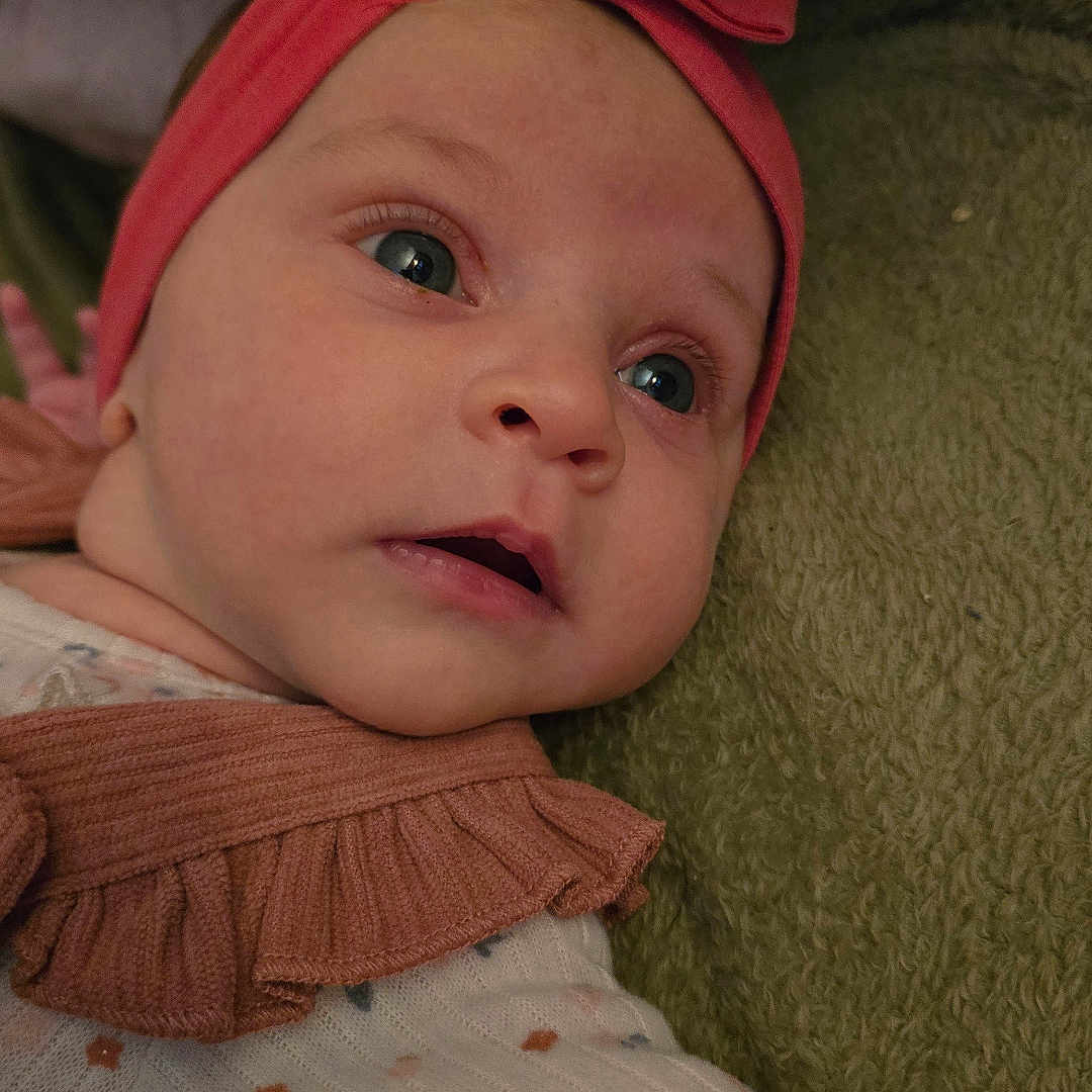 Cataleya a rejoint le concours — aidez-le/la à gagner de superbes lots ! baby, blanket, bow, child, closeup, clothing, curious, cute, eyes, face, floral, green, headband, infant, person, pink, portrait, ruffle, soft, texture