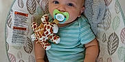 Theo is registered to the contest to win money with this photo: baby, baby_seat, blue, child, comfort, cute, giraffe, green, indoor, infant, onesie, pacifier, pattern, plush_toy, relaxed, seat, small_child, soft_toy, striped_clothing, toy