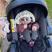 Anaë a rejoint le concours — aidez-le/la à gagner de superbes lots ! baby, car_seat, sunglasses, hat, baby_clothing, infant, stroller, outdoor, sidewalk, grass, shadow, pacifier, toy, footwear, blue_socks, casual, child, baby_accessories, sun_hat, cute