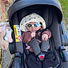 baby, car_seat, sunglasses, hat, baby_clothing, infant, stroller, outdoor, sidewalk, grass, shadow, pacifier, toy, footwear, blue_socks, casual, child, baby_accessories, sun_hat, cute