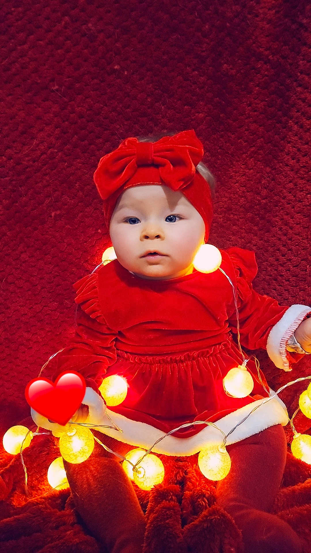 Zélia participe au concours pour gagner de l'argent avec cette photo : baby, child, red_dress, headband, bow, fairy_lights, glowing_lights, blanket, red_background, holiday_theme, festive, cute, portrait, sitting, indoors, warm_lighting, soft_texture, toddler, holiday_outfit, cozy