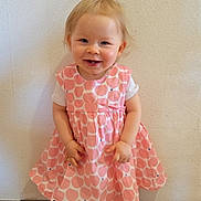 Zélia a rejoint le concours — aidez-le/la à gagner de superbes lots ! toddler, child, smiling, standing, dress, pink, pattern, sandals, footwear, indoor, wall, floor, happy, person, cute, short_hair, skin, small_person, baby, portrait